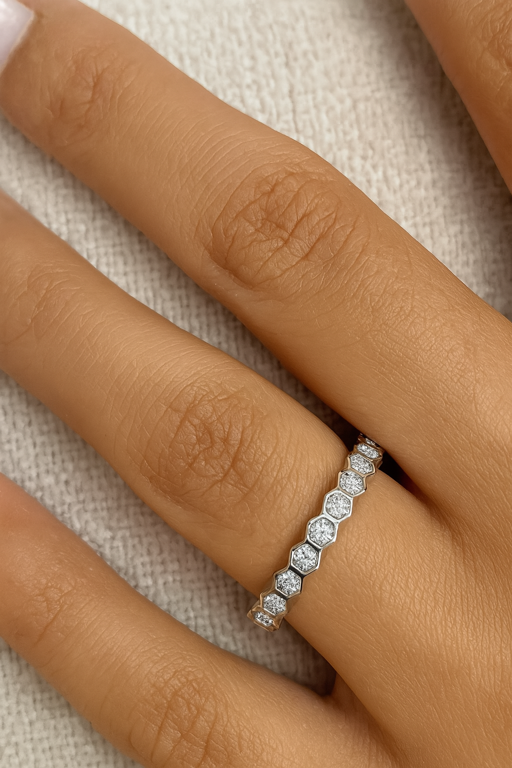 Diamond ring on a person's finger with a neutral background